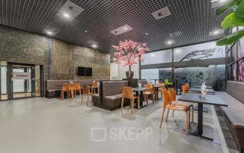Moderne zithoek in kantoorpand op Oostmaaslaan 71, Rotterdam Kralingen met houten stoelen, banken en een grote decoratieve boom.