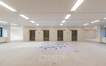 Ruime open kantoorruimte in Rotterdam Kralingen op Oostmaaslaan 71, met witte muren, vloeren en vier liften.