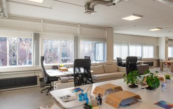 Binnenzicht van een ruime kantoorruimte huren op Linker Rottekade 292, Rotterdam Noord, met grote ramen die natuurlijk licht binnenlaten, moderne meubels en een open werkruimte met bureaus en kantoorbenodigdheden.