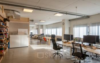 Lichte kantoorruimte met grote ramen op Linker Rottekade 292 in Rotterdam Noord, ingericht met bureaus en stoelen, ideaal voor huur als open kantooromgeving voor flexibele werkplekken.