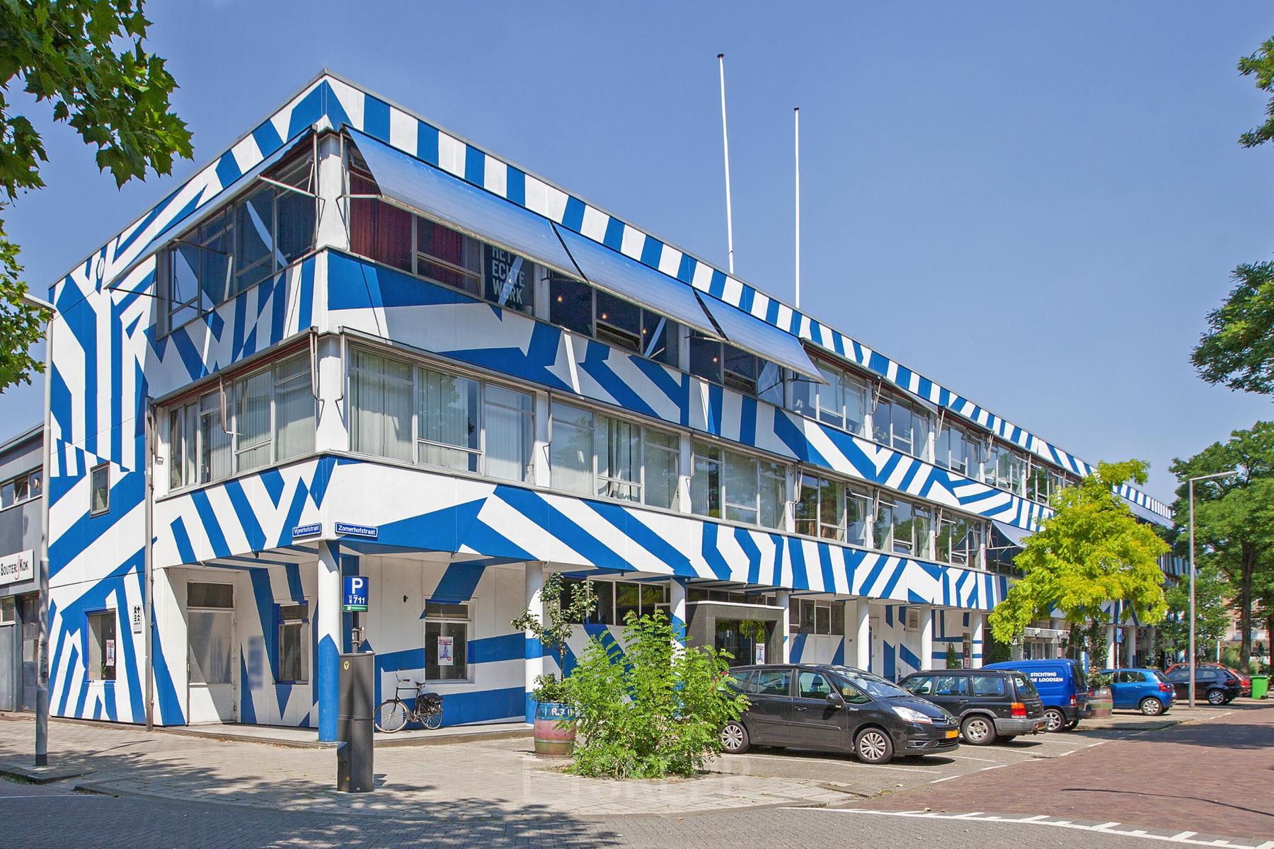 Het opvallende blauw-wit gestreepte kantoorpand op Zomerhofstraat 71 in Rotterdam Noord, met geparkeerde auto's ervoor.