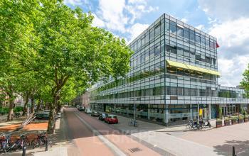 Kantoorpand aan de Vijverhofstraat 47, Rotterdam Noord. Modern gebouw met glazen gevels, omringd door bomen en geparkeerde auto's. Ideaal om een kantoorruimte te huren.