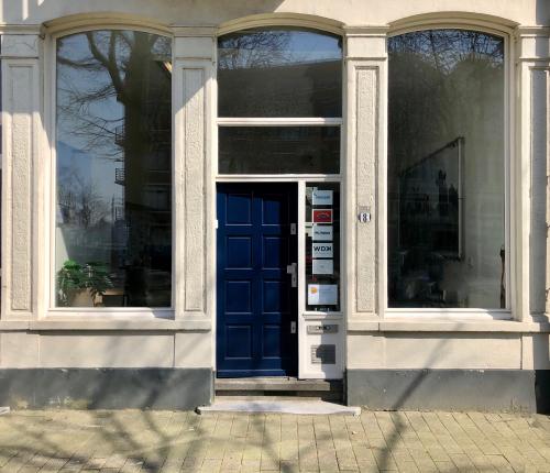Karakteristieke entree van een kantoorpand aan de Van der Takstraat 8 in Rotterdam Noordereiland, met een blauwe deur en heldere ramen.