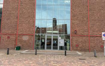 Entree van kantoorpand aan de Scheepsbouwweg 29 in Rotterdam Waalhaven, met bakstenen gevel en grote glazen façade, ideaal voor wie kantoorruimte wil huren.