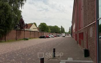 Kantoorpand aan de Scheepsbouwweg 29 in Rotterdam Waalhaven, met een lange, rode gevel en geparkeerde auto's langs de straat. Geschikt voor kantoorruimte huren.