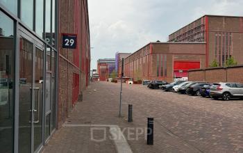 Bakstenen exterieur van kantoorpand op Scheepsbouwweg 29, Rotterdam Waalhaven, met parkeerplaatsen en een rustige straat. Ideale locatie voor kantoorruimte huren.