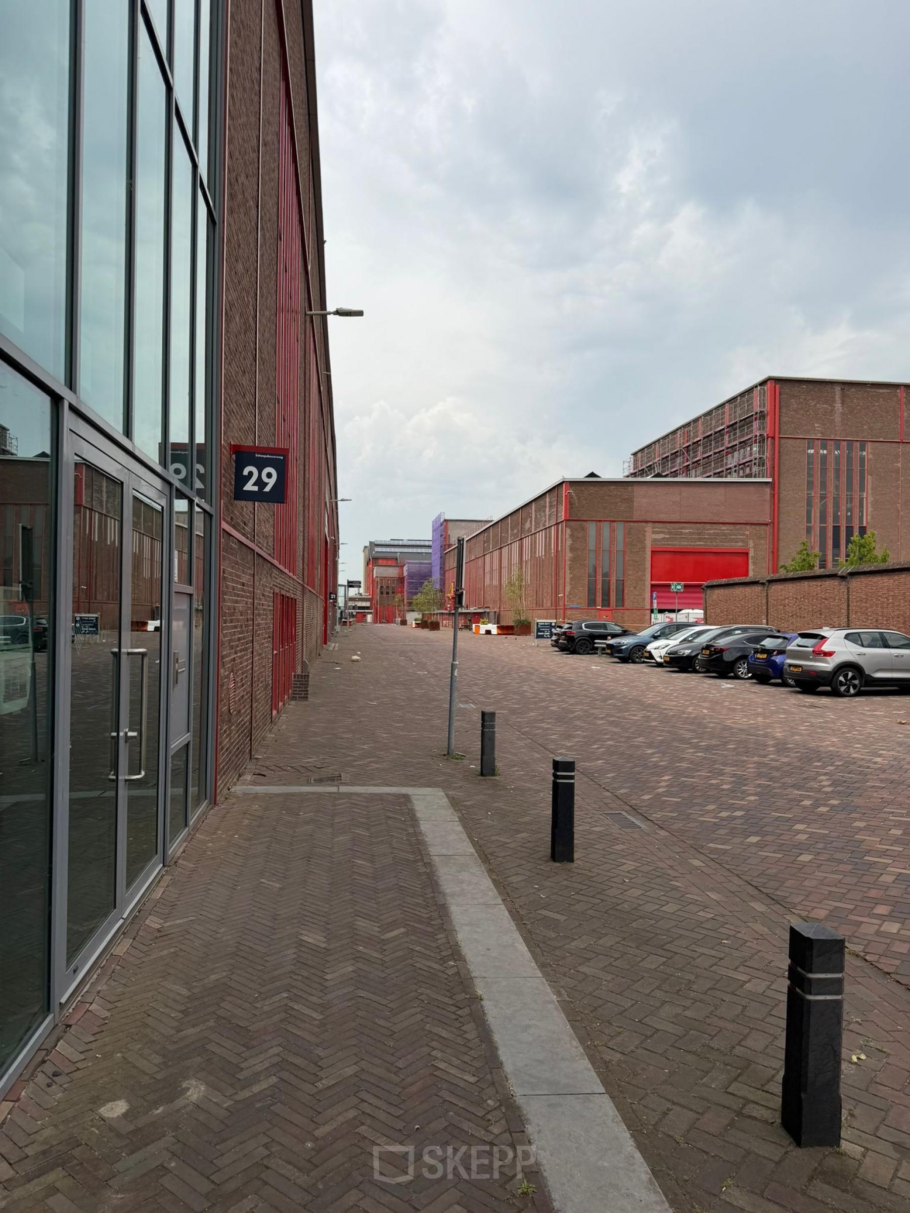 Bakstenen exterieur van kantoorpand op Scheepsbouwweg 29, Rotterdam Waalhaven, met parkeerplaatsen en een rustige straat. Ideale locatie voor kantoorruimte huren.