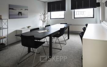 small meeting room with black tables and chairs