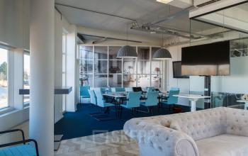 Kantoorruimte huren aan Overschieseweg 34, Schiedam, met vergadertafel, stoelen, relaxte bank en grote ramen die veel licht binnenlaten.