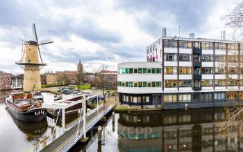 Exterieur van kantoorpand op Noordvest 18, Schiedam, met uitzicht op historische molen langs het water.
