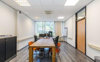 Ruime kantoorpand met moderne afwerking op Noordvest 18, Schiedam. Voorzien van lange tafel met comfortabele stoelen, ideaal voor vergaderingen of als flexibele kantoorruimte. Veel natuurlijke lichtinval door grote ramen.