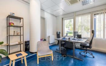 Kantoorpand aan Noordvest 18 in Schiedam, met een werkplek bestaande uit twee bureaus, stoelen en een kast. De ruimte is licht en uitnodigend, ideaal voor kantoorruimte huren.