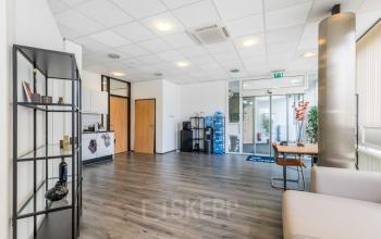 Kantoor op Noordvest 18 in Schiedam met een moderne uitstraling. De ruimte is gemeubileerd met een bank, tafels, en decoratieve rekken. Perfect voor kantoorruimte huren.