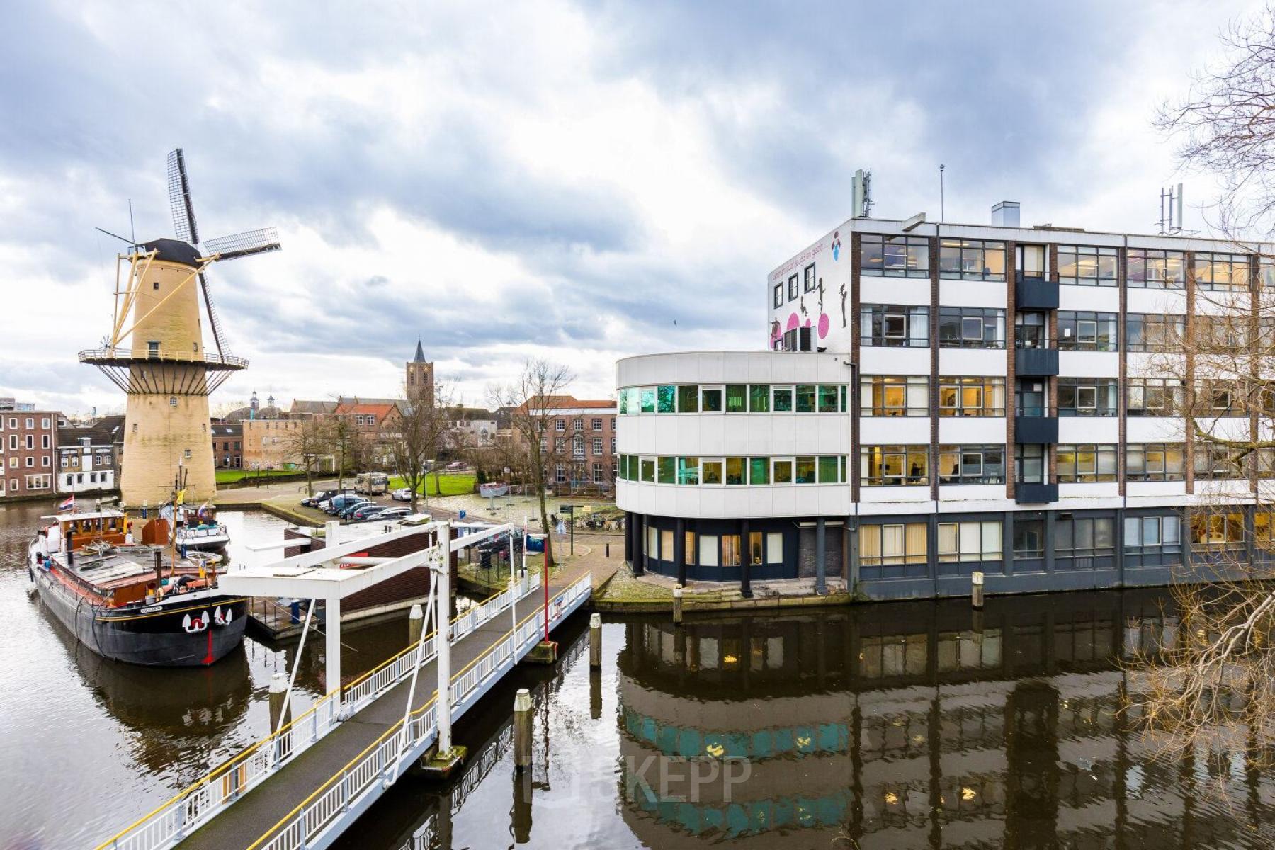Exterieur van kantoorpand op Noordvest 18, Schiedam, met uitzicht op historische molen langs het water.