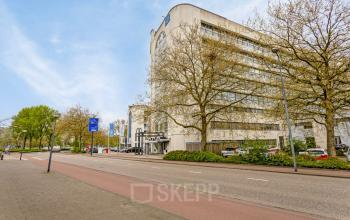 Buitenaanzicht van kantoorpand aan de Brauwweg 52-66 in Schiedam, met moderne architectuur omgeven door bomen en geparkeerde auto's.