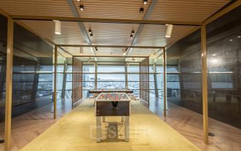 Kantoorruimte huren op Schiphol Boulevard 127 met een speelse vergaderruimte voorzien van een tafelvoetbaltafel, houten plafond en grote ramen met uitzicht over Schiphol Airport.