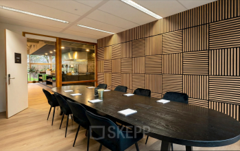 Moderne vergaderruimte in kantoorpand Boeing Avenue 1-19, Schiphol Rijk met houten muren, een lange zwarte tafel en gestoffeerde stoelen.