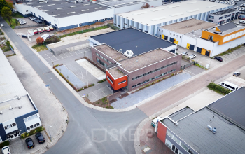 Luchtfoto van een kantoorpand op Fischerpad 106 in Sittard, omgeven door parkeerplaatsen en bedrijfsgebouwen.