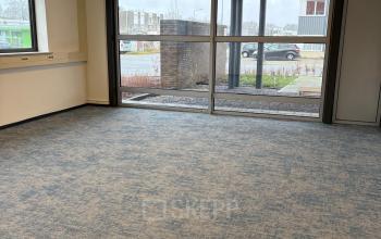 Lege kantoorruimte met grote ramen en blauw tapijt op Fischerpad 106, Sittard, beschikbaar om te huren.