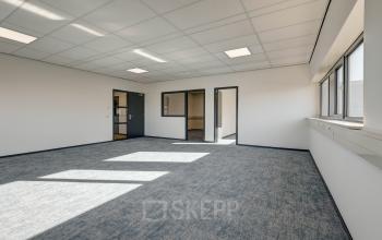 Leeg kantoor in Sittard met ramen en tapijt, klaar om te huren als werkruimte in kantoorpand.