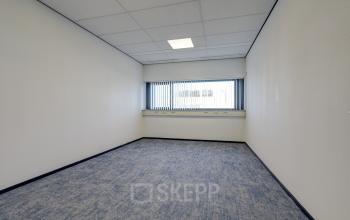 Lege kantoorruimte met blauw tapijt en witgeschilderde muren op Fischerpad 106, Sittard, geschikt voor kantoorruimte huren.