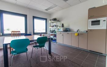 Kantoorruimte huren in Sittard op Nusterweg 63 met ingerichte keuken, eettafel en diverse stoelen, geschikt voor verschillende activiteiten.