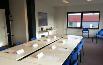 Ruime kantoorruimte op Nusterweg 63 in Sittard, ingericht met vergadertafels en blauwe stoelen, klaar voor gebruik door huurders. De ruimte heeft veel daglicht en is ideaal voor zowel vergaderingen als presentaties.