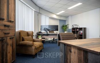 Gezellige kantoorruimte huren op Stationsplein 1 in Sittard, met bruine leren stoelen, houten bureau en kasten, en grote ramen voor veel natuurlijk licht.