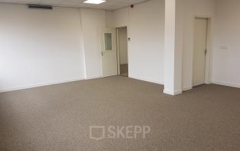 Leeg kantoorpand aan Stationsplein 1 in Sittard met tapijt vloer en witte muren, klaar om ingericht te worden voor verhuur.