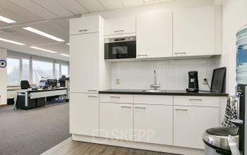 Interieur van een kantoor op Curieweg 7, Spijkenisse met een kitchenette, bureaus en stoelen. Perfecte plek voor kantoren huren. Heldere ruimte, ideaal voor zakelijke productiviteit.