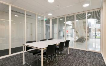 Vergaderruimte in kantoorpand op Curieweg 7, Spijkenisse. Kamer met glazen wanden, tafel en stoelen, modern interieur. Zakelijke omgeving.