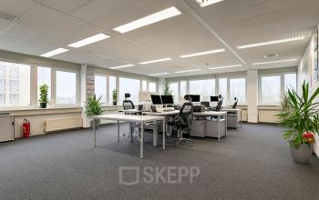 Kantoorruimte huren aan de Curieweg 7 in Spijkenisse, licht en ruim met moderne werkplekken, grote ramen en planten.