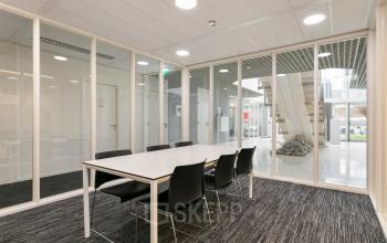 Zicht op een moderne vergaderruimte in het kantoorpand aan de Curieweg 7 in Spijkenisse, met een tafel en zes stoelen. Ideaal voor bedrijven die kantoorruimte willen huren.
