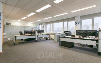 Kantoorruimte huren op Curieweg 7 in Spijkenisse met ruime werkplekken, voorzien van bureaus, stoelen en computers, gelegen in een lichtrijk interieur met grote ramen.