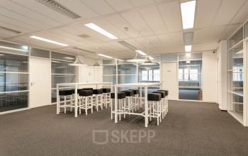 Kantoorruimte huren op Curieweg 7, Spijkenisse. Ruime, lichte werkruimte met glazen wanden, hoge tafels en barkrukken.