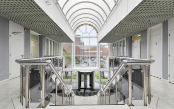 Een lichtovergoten entree in het kantoorpand op Curieweg 7, Spijkenisse, met een indrukwekkende glazen boog en moderne architectuur. Ideaal voor wie kantoorruimte wil huren met een stijlvolle uitstraling.