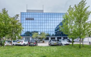 Vooraanzicht van een modern kantoorpand gelegen aan de Curieweg 9, Spijkenisse, met een glazen gevel en parkeerruimte. Ideaal voor wie kantoorruimte wil huren in een strak en professioneel gebouw.