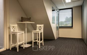 Kantoorruimte huren aan Curieweg 9 in Spijkenisse met twee hoge witte krukken en een tafel, minimalistisch ingericht en geschikt voor zakelijke gesprekken of ontspanning.