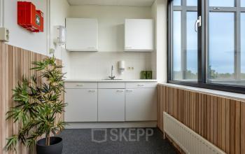 Compacte kitchenette in het kantoorpand aan Curieweg 9, Spijkenisse, met houten details en uitzicht naar buiten. Ideaal voor een kleine pauzeruimte bij het huren van een kantoorruimte.