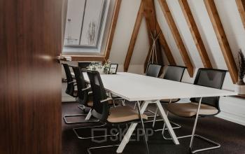 Ruime vergaderruimte met houten balken en moderne stoelen in kantoorpand op Bredaseweg 8, ideaal voor kantoorruimte huren in Breda Terheijden.