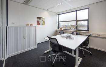 werkplek tilburg huur kantoorruimte tafel stoelen raam kast uitzicht vloerbedekking schilderij