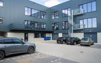 Buitenaanzicht van een modern kantoorpand op Kapitein Rondairestraat 8 in Tilburg met meerdere parkeerplaatsen voor de deur.