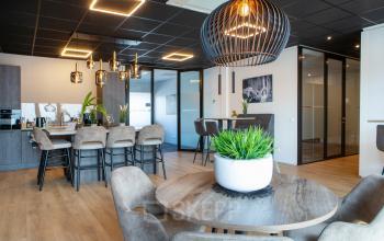 Stijlvol ingerichte kantoorruimte met houten vloeren, moderne verlichting en verschillende zitgelegenheden op Kapitein Rondairestraat 8 in Tilburg. Mogelijkheid om dit kantoorpand te huren voor een inspirerende werkomgeving.