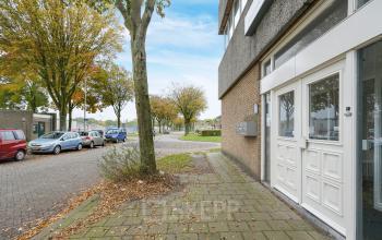 Buitenkant van kantoorpand gelegen op Jules de Beerstraat 14 in Tilburg, met parkeerplaatsen en bomen langs de straat.