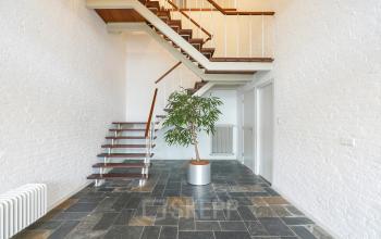 Entree van het kantoorpand aan Jules de Beerstraat 14, Tilburg, met natuurstenen vloer, plantenbak en houten trap. Kantoorruimte huren mogelijk.