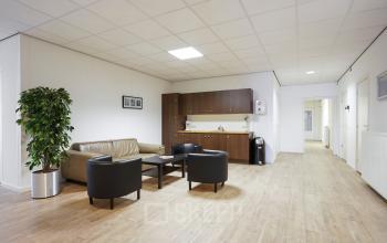 Interieur van een kantoorpand gelegen aan de Jules de Beerstraat 14 in Tilburg, voorzien van een zithoek met stoelen, tafels en wastafelmeubel