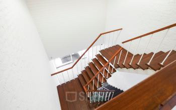 Trappenhuis met houten traptreden en witte muren in kantoorpand op Jules de Beerstraat 14, Tilburg. Rustige en lichte omgeving voor kantoorruimte huren.