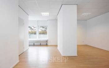 Ongemeubileerd kantoorpand voor huur op Jules de Beerstraat 14, Tilburg, met houten vloeren, witte muren en grote ramen voor natuurlijk licht.