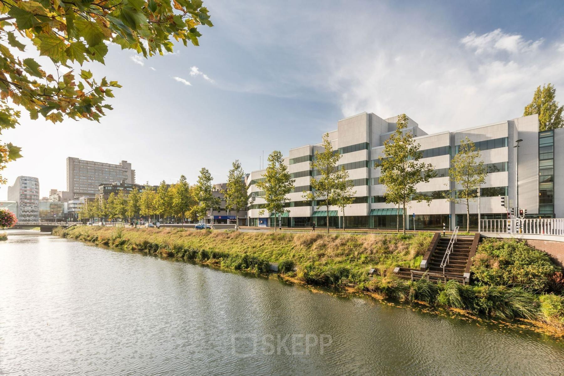 Kantoorpand aan de Daalsesingel 51, Utrecht Centraal Station, met uitzicht op het water, omringd door groen.