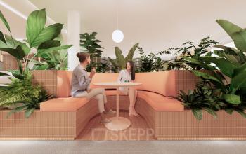 Sfeervolle kantoorruimte bij Moreelsepark 1 in Utrecht Centraal Station met uitnodigende zitgelegenheden omringd door groene planten en zakelijke gesprekken aan een ronde tafel. Optimaal voor creatieve interacties.